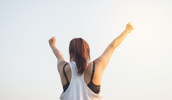 A woman celebrating her success after weight loss surgery, raising her arms in triumph.