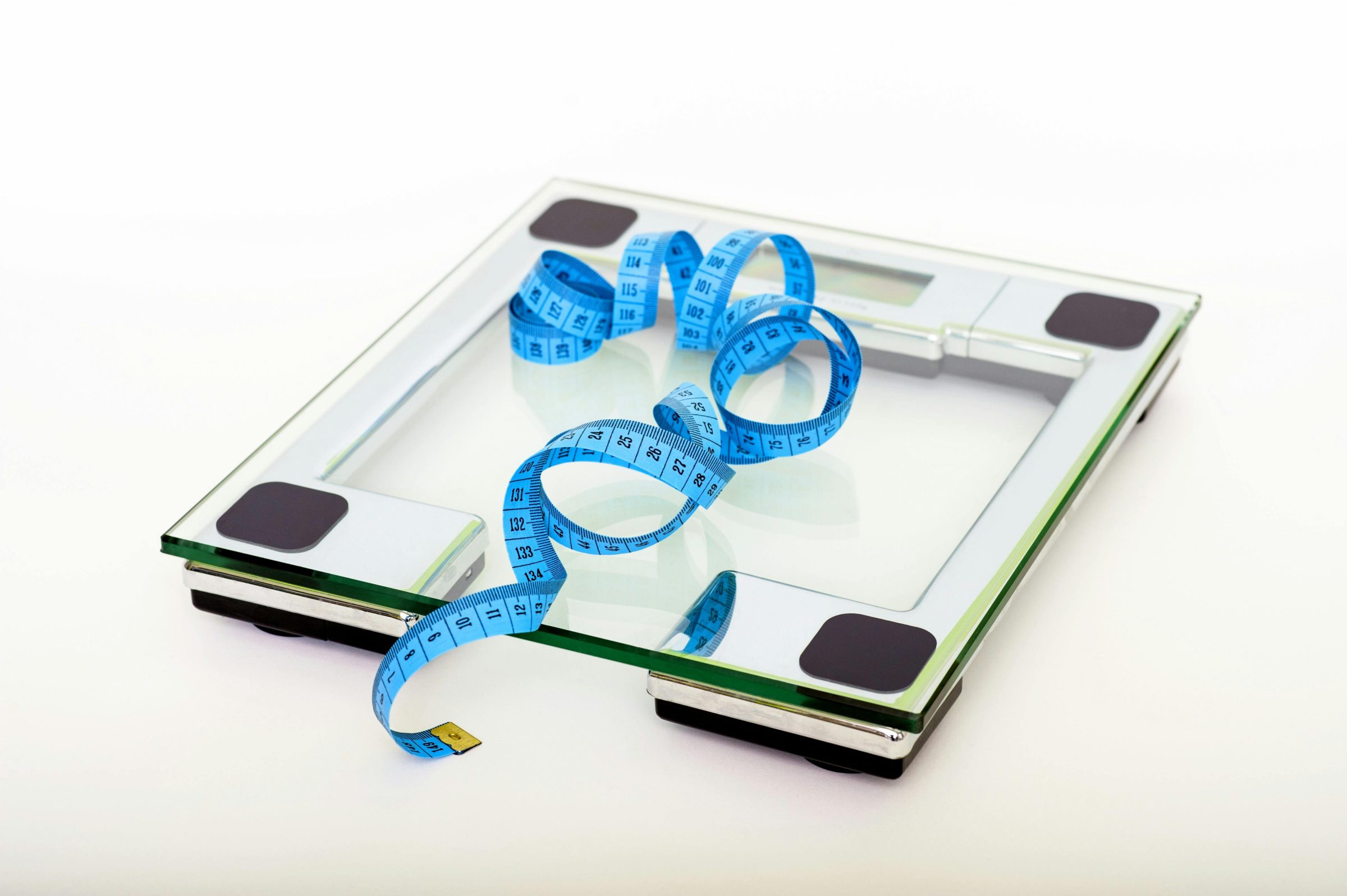 A scale with a measuring tape beside it, symbolizing the journey of weight loss surgery and progress tracking.